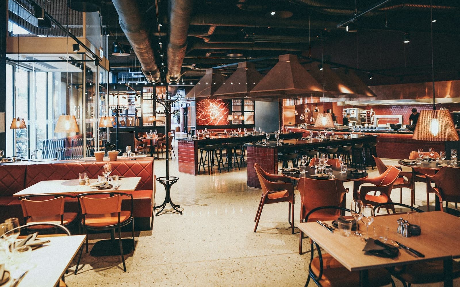 Salle de brasserie en service, tables dressées et banquettes.